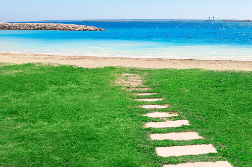 Green grass and footpath at beach . Idyllic beach with turquoise color sea