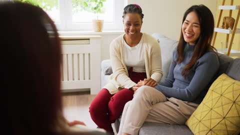 Cheerful multiracial lesbian couple, at the couple therapy led by female therapist