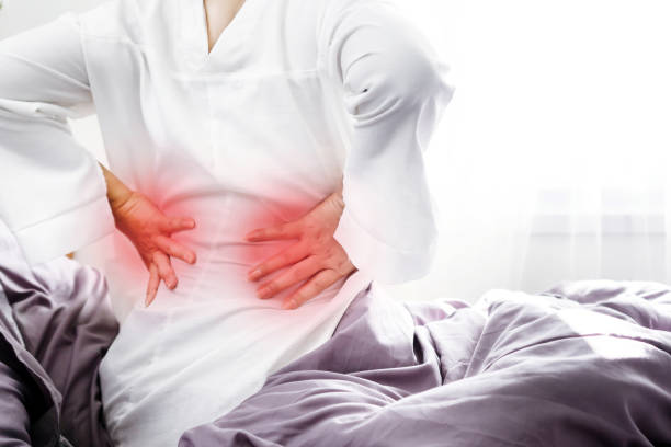 Morning Discomfort with Woman Wakes Up with Lower Back Pain from Poor Sleeping Posture stock photo