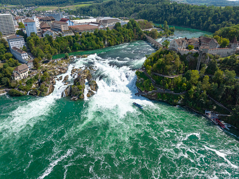 Rhine Falls waterfall in Schaffhausen, Switzerland seen from above with the Schloss Laufen on top of the cliff. The Rheinfall in the river Rhine is the most powerful waterfall in Europe.