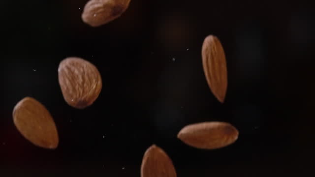 Slow motion of Almond seeds falling on dark background
