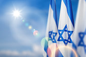 Israel flags with a star of David over cloudy sky background. Banner with place for text.