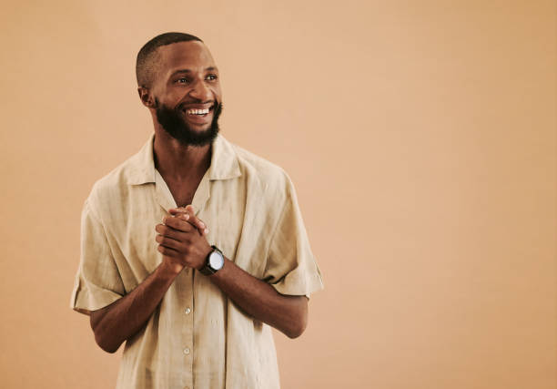 istock Happy young black man standing looking away from the camera whilst clasping his hands together with copy space, stock photo 1489077949