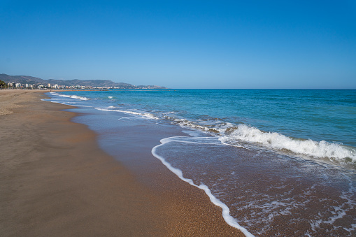 A wide sandy beach of the Mediterranean Sea in Spain. A sunny warm spring day.