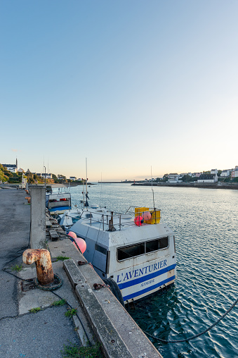 View towards the mouth of the River Goyen into the Atlantic Ocean in the last rays of the sun and a blue sky. The fishing boats are close to La Cotriade fish market and the Poulgoazec Smokehouse. In the immediate vicinity of the municipality of Audierne in Cornouaille. 09/23/2022 - Quai Jean Jade, 29780 Plouhinec, Department Finistere, Arrondissement Quimper, Bretagne, France