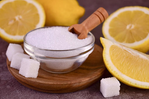 Citric acid in a bowl and fresh lemons.Close-up.