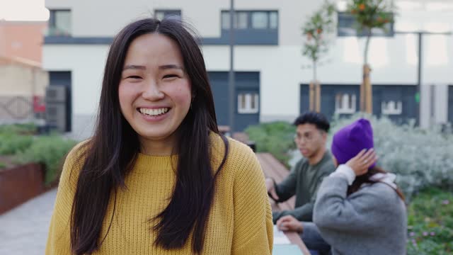 Young student asian woman smiling at camera sitting at college campus
