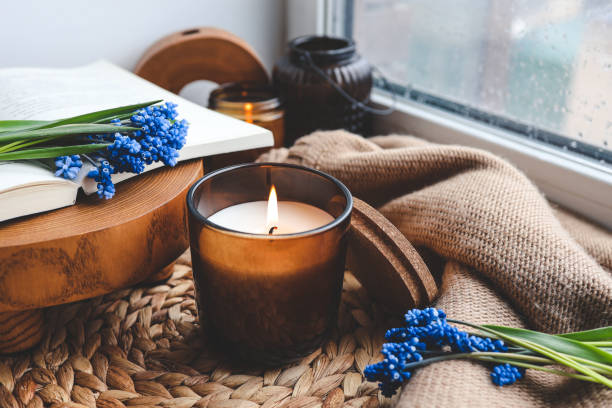 istock Burning candle and spring flowers on the windowsill in the home interior 1489084390