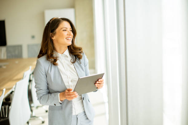 istock Young woman working on digital tablet by the office window 1489084601