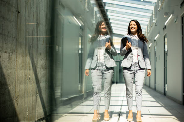 istock Young woman walking with digital tablet in the office hallway 1489084628