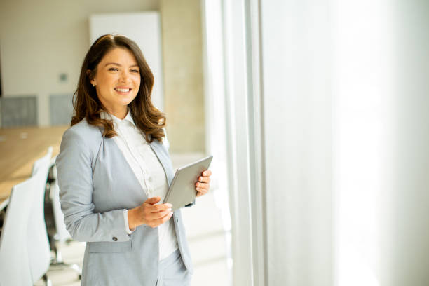 istock Young woman working on digital tablet by the office window 1489084640