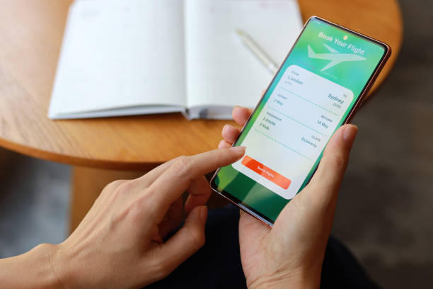 istock An over-the-shoulder view captures a woman using a smartphone application to book flight tickets and plan her holiday trip. 1489084979