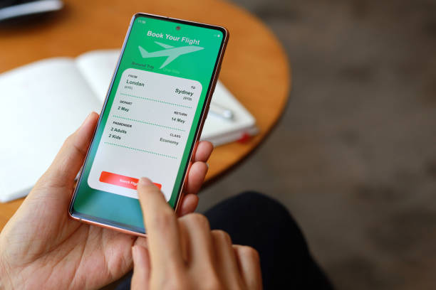 une vue par-dessus l’épaule capture une femme utilisant une application pour smartphone pour réserver des billets d’avion et planifier son voyage de vacances. - airplane ticket ticket airplane internet photos et images de collection