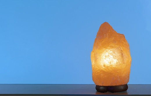 Himalayan salt lamp with the ability to ionize the air on a blue background