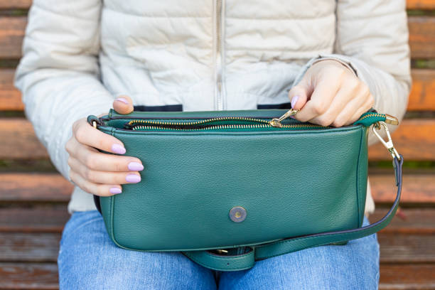 istock woman opens handbag while sitting on a bench 1489088240
