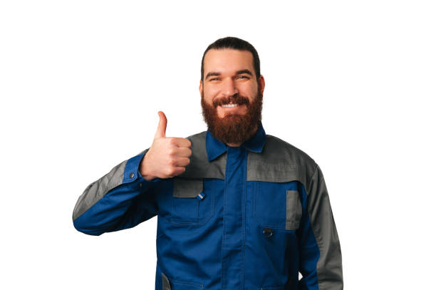 istock Cheerful young bearded handyman wearing blue uniform is holding a thumb up. 1489088877