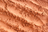 Red terracotta bentonite clay powder texture. Natural beauty treatment and spa. Clay texture macro, selective focus. Abstract background.