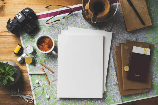 Travel concept flat lay, blank white magazine stack mockup Travel concept flat lay table top shot on wooden background. Map, coffee, passport, glasses, earphones, succulent, pencils, notebook, camera and film rolls on the table with white blank cover magazine stack. attraction studio photography stock pictures, royalty-free photos & images