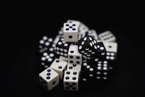 A close up of white and black dice isolated on a black background