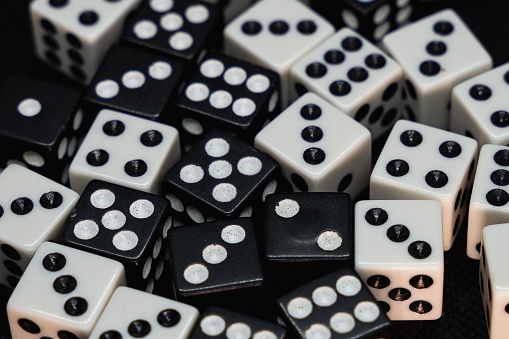 A close up of white and black dice isolated on a black background