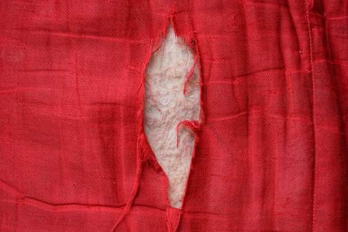part of an old red torn fabric with a big white hole