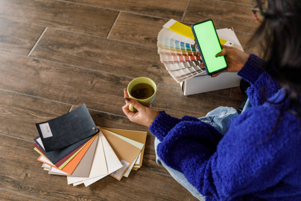 istock Young woman having coffee and using smart phone with chroma key on the screen when moving into new home 1489095065