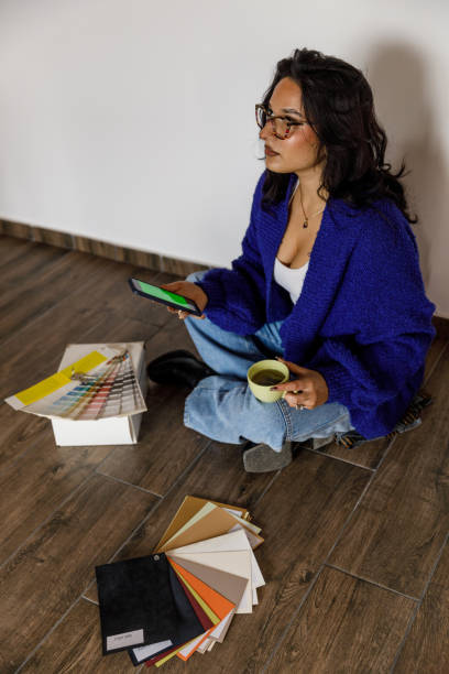 istock Young woman having coffee and using smart phone with chroma key on the screen when moving into new home 1489095519