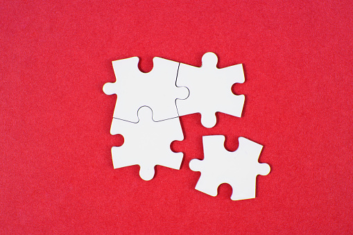 White puzzle pieces comes together on red background