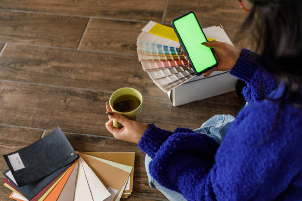istock Young woman having coffee and using smart phone with chroma key on the screen when moving into new home 1489095658