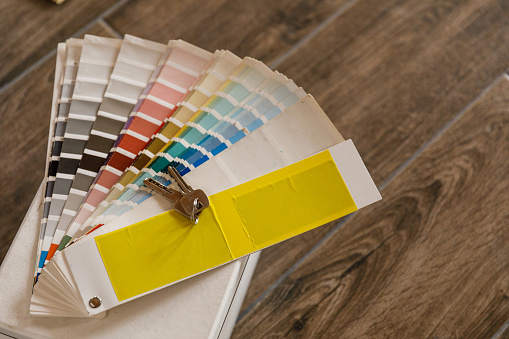 Happy young woman smiles while choosing a paint color for her new home. She holding a couple of color swatches while choosing another.