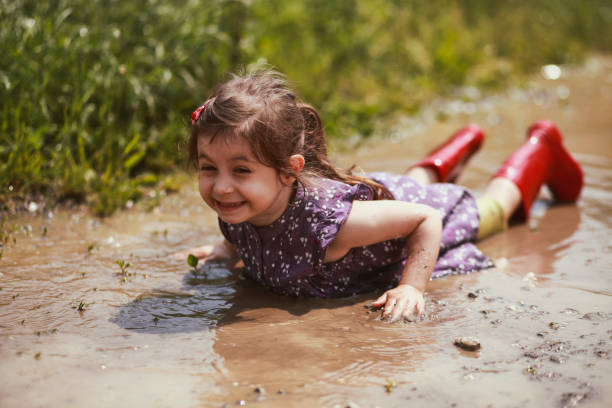 Little girl had an accident and is lying in a puddle. But enjoying it.