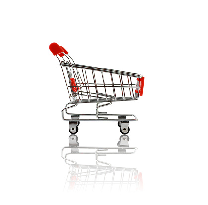 One-year-old baby accompanies her mother to do the grocery shopping riding in the grocery shopping cart while she touches the fruits