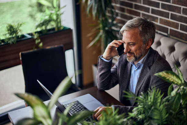 istock A busy senior male restaurant owner using a mobile phone while working over the laptop. 1489105939
