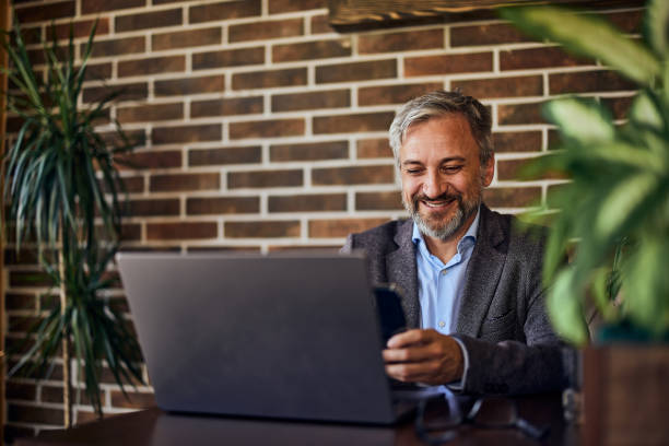 istock A smiling male employer using a mobile phone while sitting in front of a laptop. 1489105940