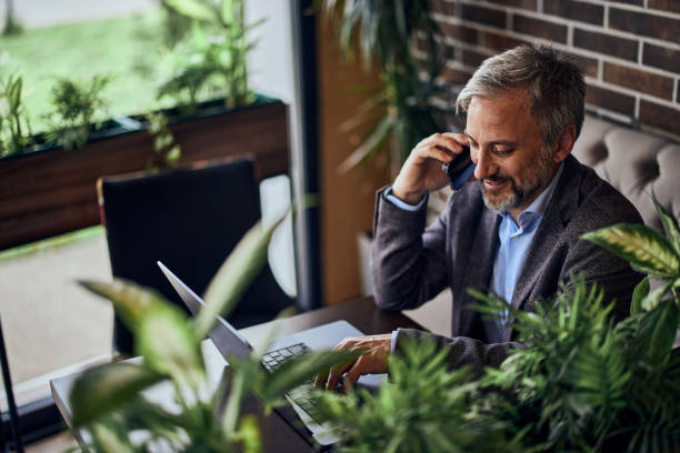 istock Top view of a smiling restaurant owner, using a mobile phone and laptop. 1489105953