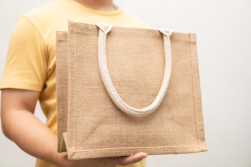 Man holding jute bag or sack bag on white background. Reusable shopping bag. Plastic free. Eco friendly concept. Sack bag for reusable shopping lifestyles, ecology business concept.