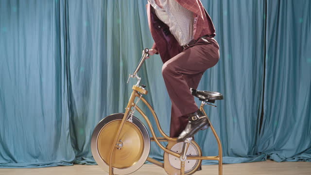 Retro Man Riding Vintage Exercise Bike in Broadcast Setting