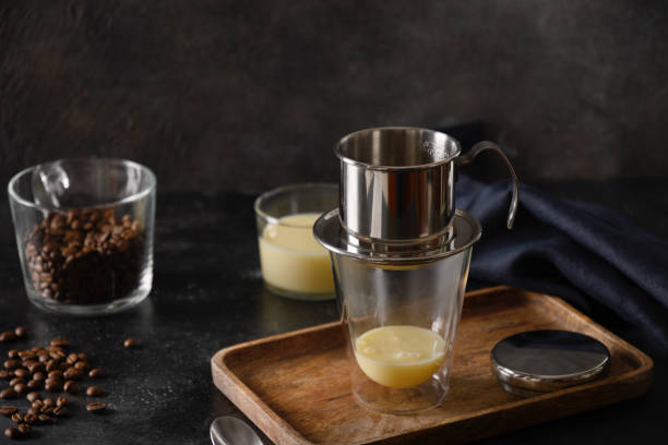 Pouring water in drip filter for cooking Vietnamese coffee with sweet condensed milk.