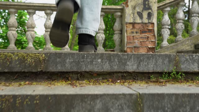 Woman legs in jeans walking on ancient stair back view.