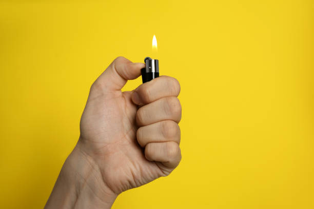 istock Man holding lighter on yellow background, closeup. Space for text 1489112014