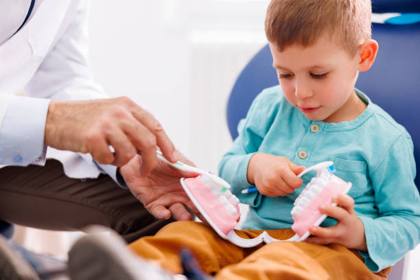 Dentist demonstrating teeth brushing to a little boy