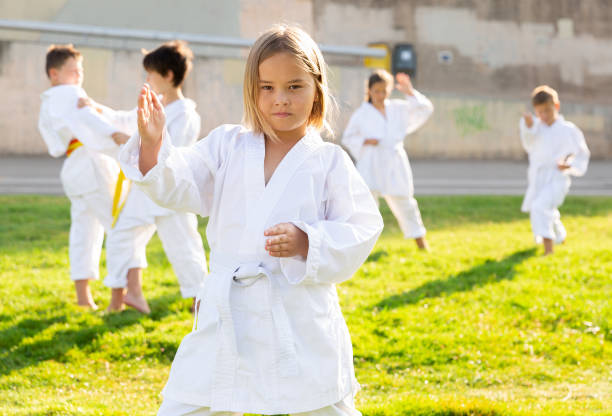 istock Tween girl exercising taekwondo techniques with group on green lawn 1489115586