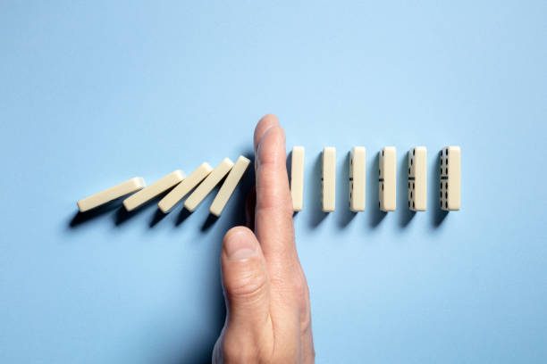 Stop the domino effect concept for business solution and intervention Stopping the domino effect concept for business solution, strategy and successful intervention hand stopping dominos stock pictures, royalty-free photos & images