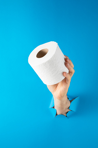 Hand holding toilet paper on blue background