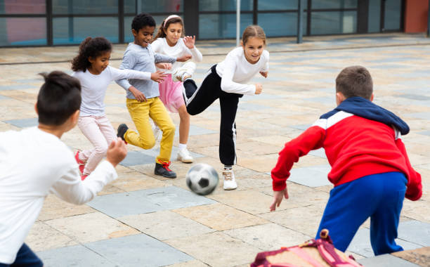 istock Cheerful tween schoolchildren playing with ball near school 1489122041