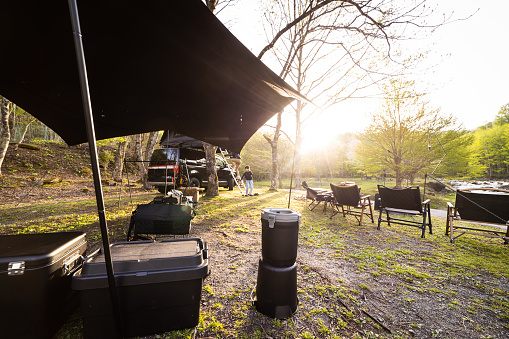 A camp set up themed in all black by a river at sunset.