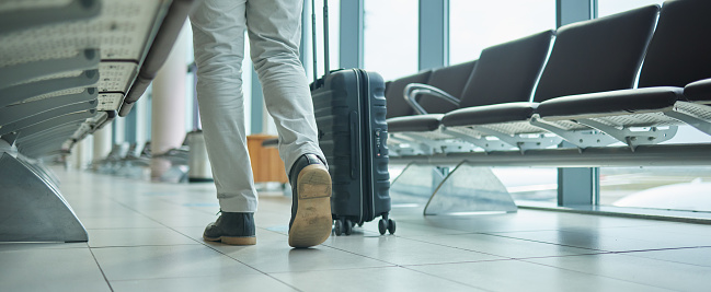 Airport, suitcase and person legs walking to flight for international opportunity or global journey in lobby. Luggage of entrepreneur or business man travel for vacation, travel agency or hospitality