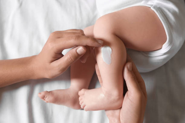 istock Mother applying moisturizing cream onto baby`s leg on bed, top view 1489125926