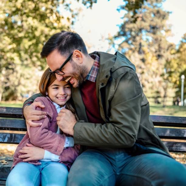 Happy father and daughter enjoying time at park stock photo