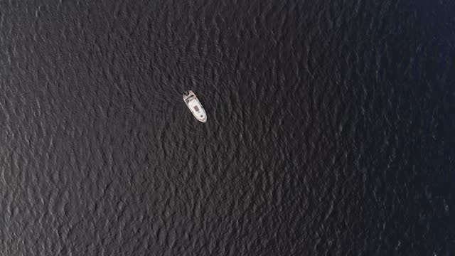 Motorboat anchored in middle of a large lake, top-down aerial view
